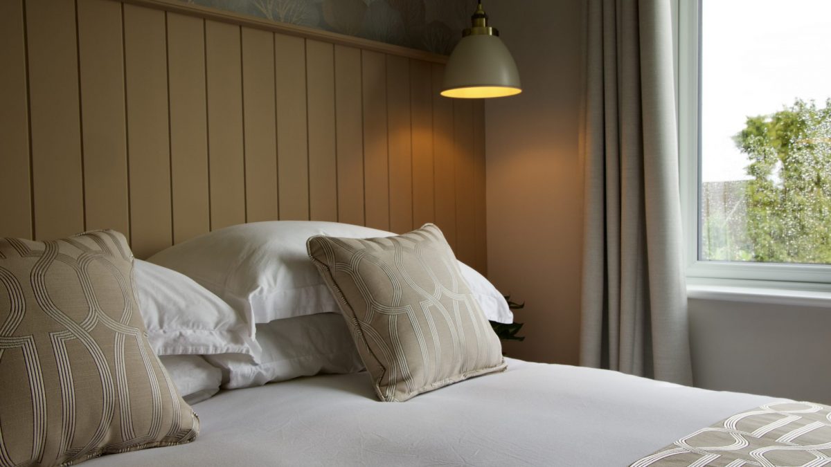 Harbur Home Bespoke Lusso Home guest bedroom with double bed, coral wallpaper, two bedside tables and over hanging lightings and wood panelled headboard design
